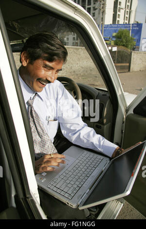 Indian businessman wearing light blue shirt and tie sitting in car and using laptop MR NO. 686B Stock Photo