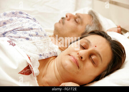 South Asian Indian middle aged couple having sound asleep on bed MR#686F,646 Stock Photo