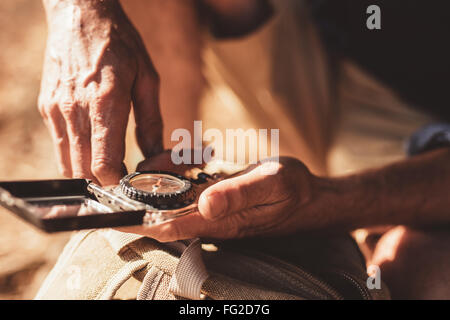 Close up portrait of man using compass for directions. Focus on compass in hands of a male hiker. Stock Photo