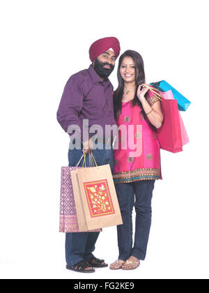 Sikh man and woman holding colourful shopping bags standing close to each other MR#702Z;779A Stock Photo