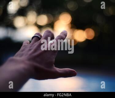 Close-Up Of Cropped Hand Pointing At Defocused Lights
