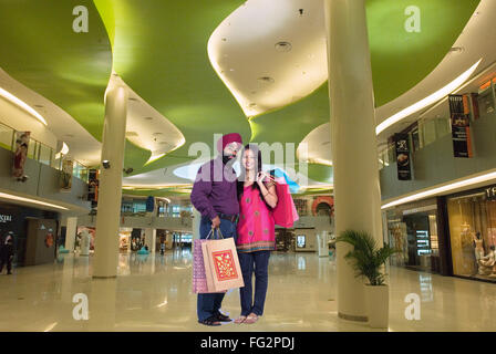 Sikh couple holding shopping bags standing in mall MR#702Z;779A Stock Photo