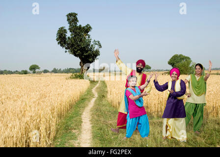 Sikh family performing folk dance bhangra in wheat field MR#702X;702Y;779A;702Z Stock Photo