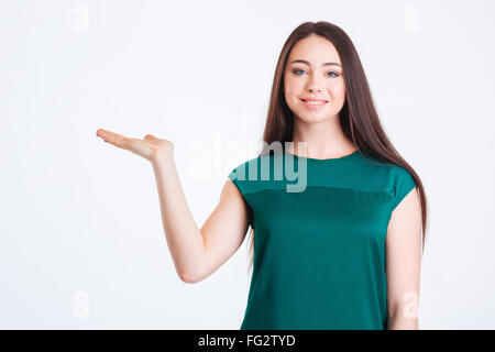 Cheerful pretty young woman standing and holding copyspace on palm over white background Stock Photo