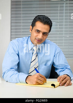 Executive looking at camera writing on notepad MR#779K Stock Photo