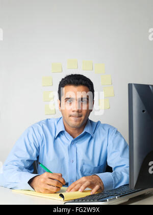Executive writing on notepad sticky notes on wall in background MR#779K Stock Photo