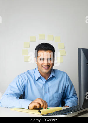 Executive writing on notepad sticky notes on wall in background MR#779K Stock Photo