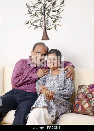 Old couple embracing sitting close to each other on sofa MR#702T,702S Stock Photo