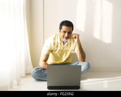 Man sitting on floor using laptop MR#779K Stock Photo