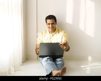 Man sitting on floor using laptop MR#779K Stock Photo