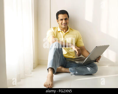 Man sitting on floor using laptop MR#779K Stock Photo