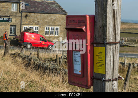 Rural postal service - Royal Mail man and van outside Stone House Inn, Thruscross, Harrogate, North Yorkshire, with the post box in the foreground. Stock Photo