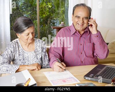 Old couple preparing legal document talking on mobile MR#702T,702S Stock Photo