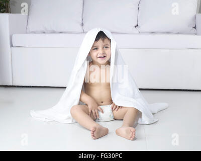 Baby playing wearing white diaper nappy towel sitting floor living room MR#779O Stock Photo