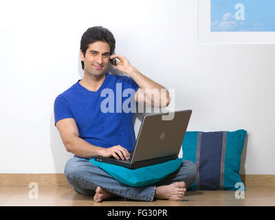Man using a laptop and talking on a mobile phone ; MR#779L Stock Photo