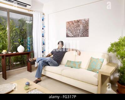 Young man sitting on sofa MR#702V Stock Photo