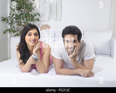 Couple lying on bed using remote control ; MR#779L  ; MR#779M Stock Photo
