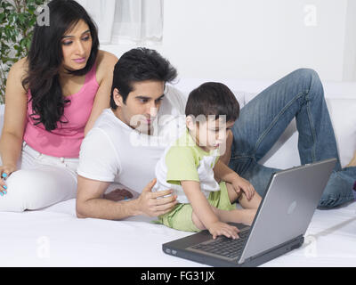 Couple using a laptop with their baby ; MR#779L ; MR#779M ; MR#779O Stock Photo