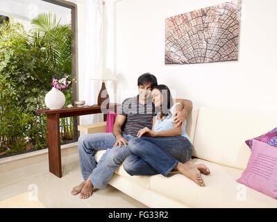 Young man and woman embracing sitting on sofa MR#702V,702U Stock Photo
