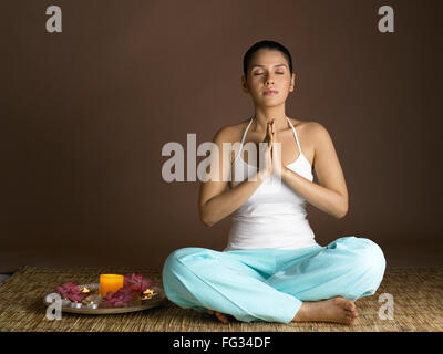 South Asian Indian woman praying with prayer utensil wearing white top and cyan pant MR # 702 Stock Photo