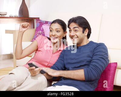 Young woman cheering and man using remote control watching TV MR#702V,702U Stock Photo