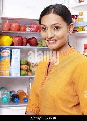 Young lady standing in front of open refrigerator MR#702U Stock Photo