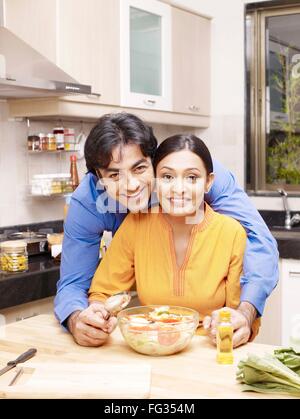 Young man standing behind woman in kitchen MR#702V Stock Photo