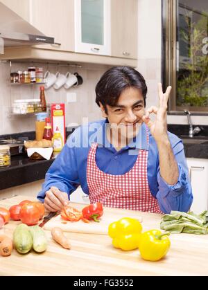Young man showing fine finger gesture sitting in kitchen MR#702V Stock Photo