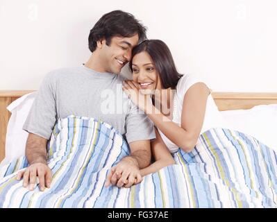 Young man and woman holding hands sitting on bed MR#702V,702U Stock Photo