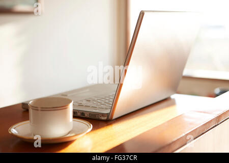 laptop computer with tea cup on wooden table Stock Photo