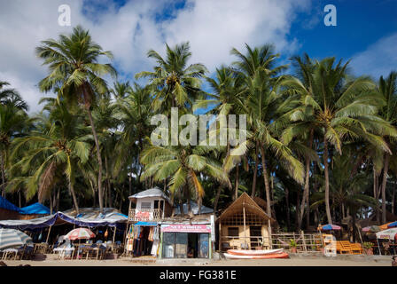 Shacks under coconut trees and boats at Palolem beach , Goa , India Stock Photo