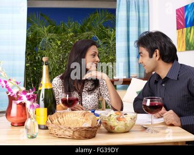 Young man and woman looking at each other sitting on dining table MR#702V, 702U Stock Photo