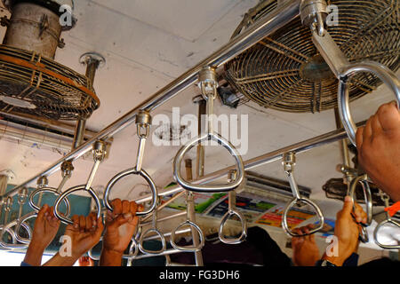 Commuters hang on in a suburban rail carriage, Mumbai India Stock Photo