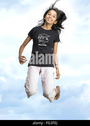 Girl jumping with joy in blue sky MR Stock Photo