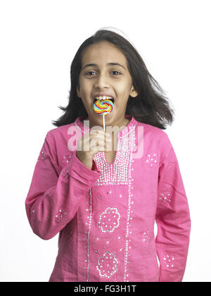 South Asian Indian girl sucking lollipop in nursery school MR Stock