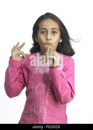 South Asian Indian girl sucking lollipop in nursery school MR Stock