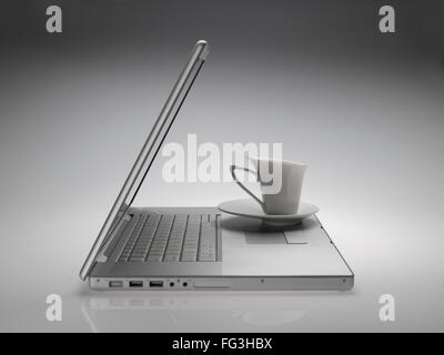 Mug with saucer on Macintosh laptop on white gray background Stock Photo