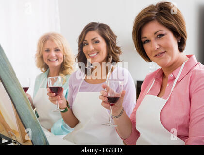 Three women holding wine glass in art studio Stock Photo