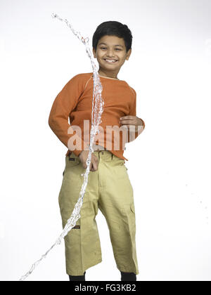 Water splashing on South Asian Indian boy in nursery school MR Stock Photo