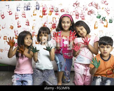 South Asian Indian boy and girls showing hand palms covered with paint in nursery school MR Stock Photo