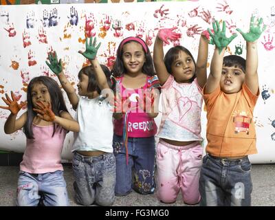 South Asian Indian boy and girls showing hand palms covered with paint in nursery school MR Stock Photo