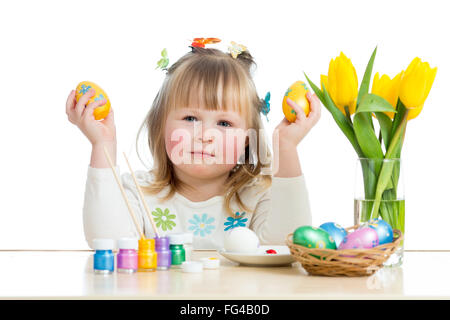 Child girl with brush coloring easter eggs Stock Photo
