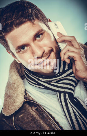 Portrait of young man with half shaved face beard hair talking on mobile phone. Handsome guy on blue. Communication technology. Stock Photo