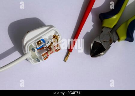 Mains electrical 240 volt plug fitted with a 3 amp fuse and electrically insulated screwdriver and pliers isolated on a white background Stock Photo