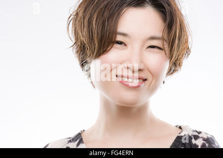 A high key headshot of a smiling, beautiful and young Japanese woman on a white background. Stock Photo