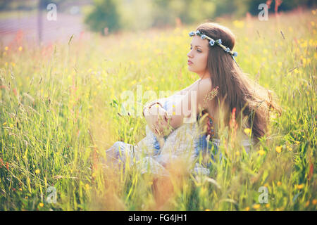 Young woman enjoying spring weather in flower field . Hippie and gypsy dress Stock Photo