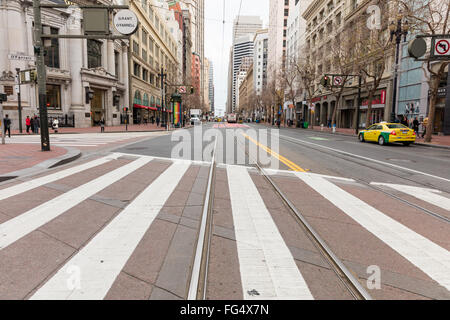 View on a street of San Francisco showing painted lines, crosswalk, street cable car tracks, bus only lanes, bicycle route