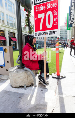 Young man holding a sign advertising a 70% sale / clearance at the local store Stock Photo