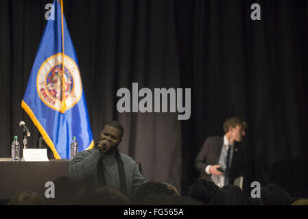 Minneapolis, Minnesota, USA. 13th Feb, 2016. An African-American activist speaks to the audience while a member of Bernie Sanders' staff leaves the backstage area. Senator Bernie Sanders of Vermont, who is seeking the Democratic Party nomination for president, attended the Black America Forum, sponsored by MN Neighborhoods Organizing for Change at Patrick Henry High School in the largely African-American neighborhood of North Minneapolis, Minnesota on Friday, February 12, 2016. After beating Hillary Clinton in the New Hampshire primary earlier in the week, Sen. Sanders began campai Stock Photo