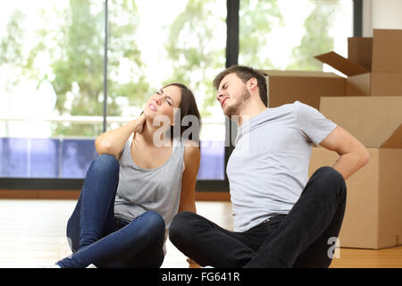 Tired couple moving home suffering backache sitting on the floor Stock Photo
